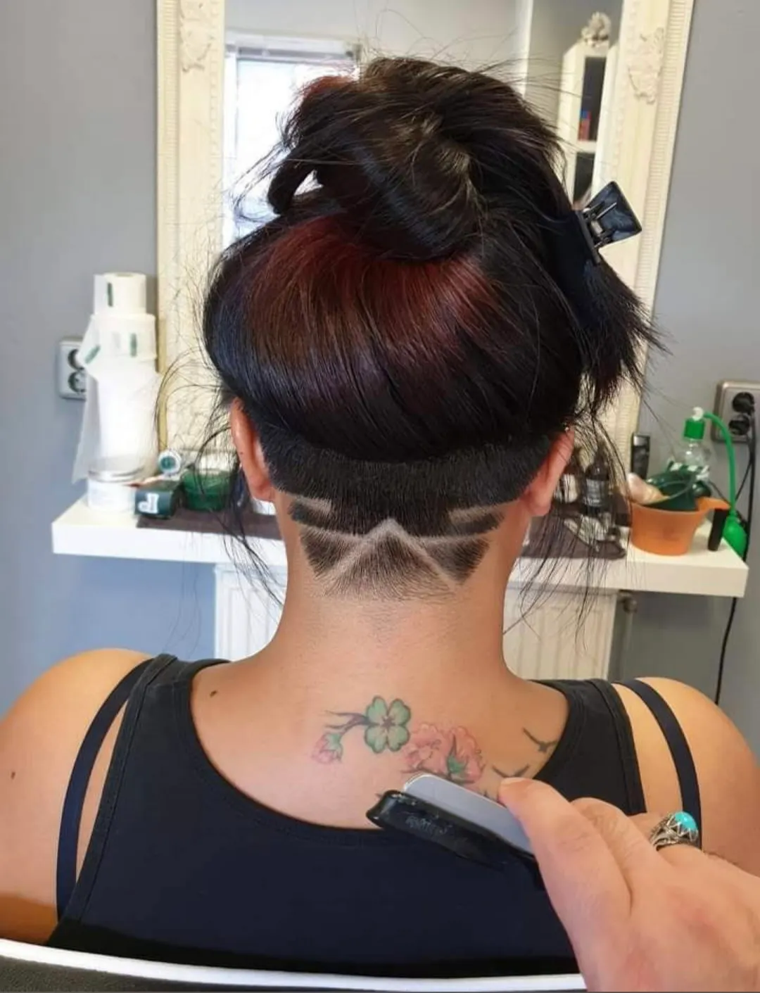 Opgestoken donker haar met een strakke undercut en een patroon in de nek